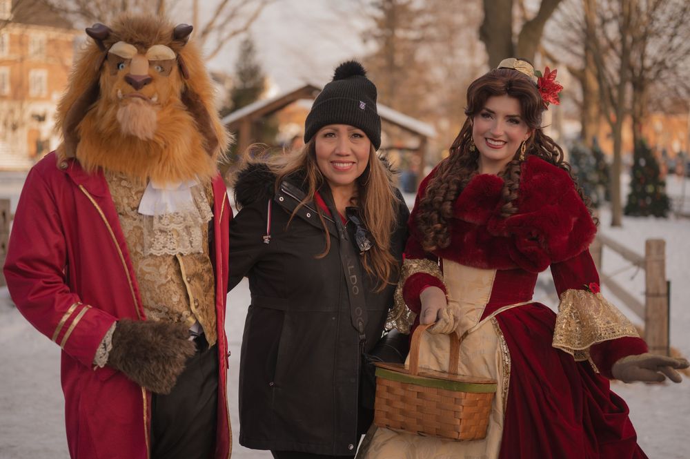 Friends in winter coats and scarves gather together outdoors during a festive holiday celebration.