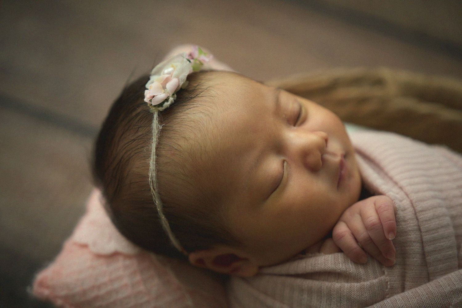 Sleeping newborn wrapped in soft gray fabric against neutral background in series of peaceful poses.