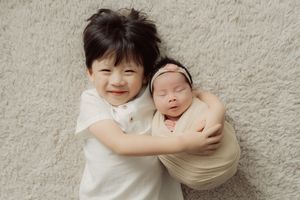 Sweet family portrait session with newborn baby and golden retriever dog against textured wall.