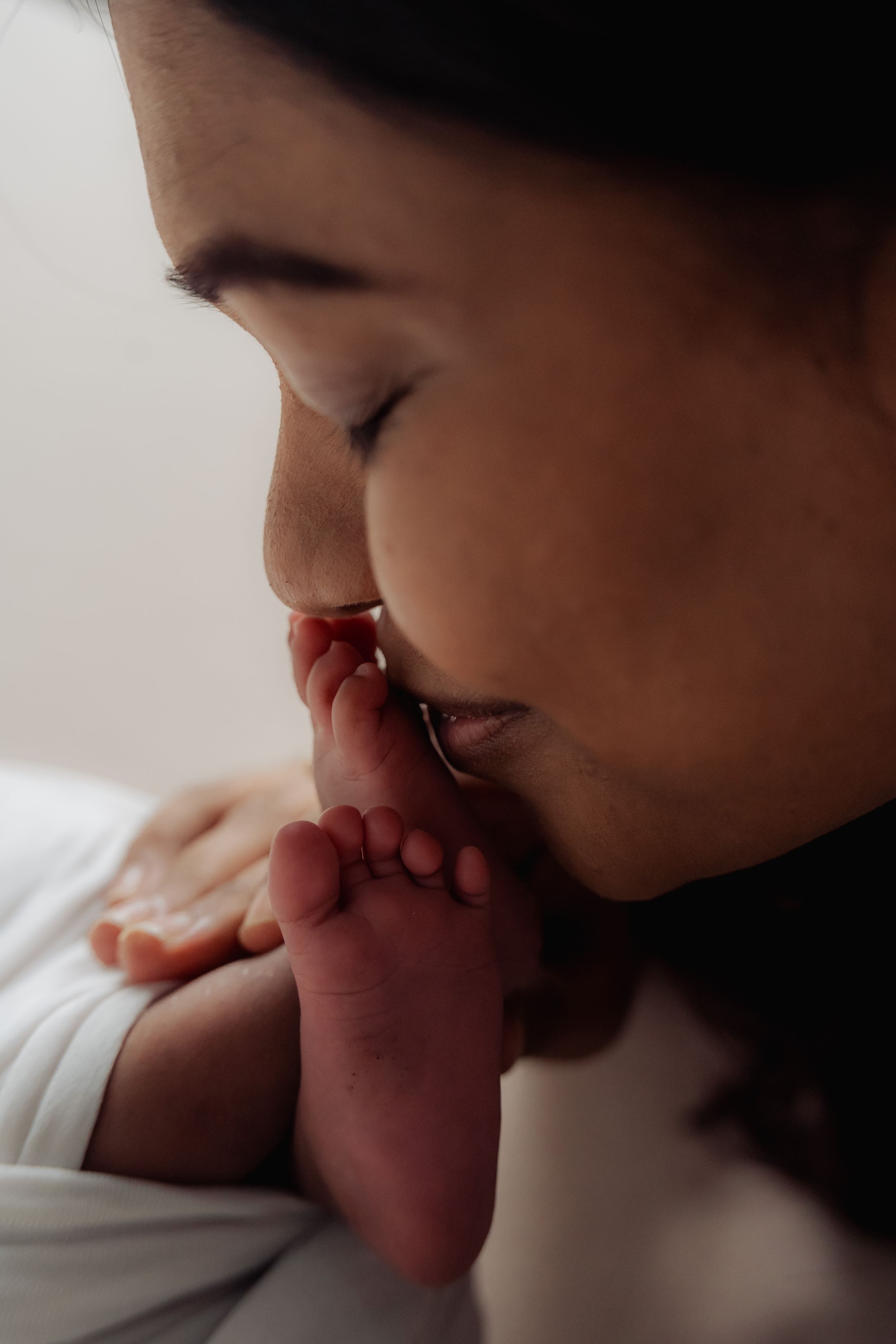 Intimate close-up of gentle kiss on tiny newborn toes.