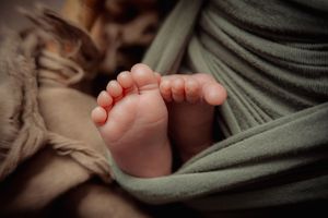 Close-up view of tiny newborn baby feet wrapped in soft fabric.