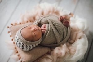 Close-up detail of newborn baby feet in soft knit booties.