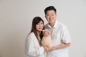 Family portrait series showing tender moments with newborn baby against white backdrop.