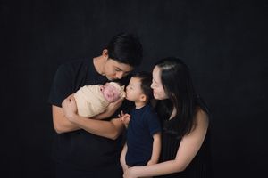 Intimate family portrait session against black backdrop.