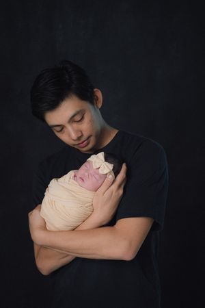 Tender moment captured against dark studio background.