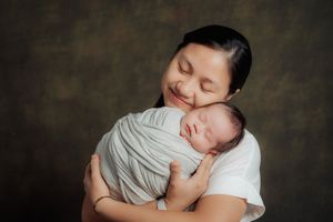 Tender moment captured of sleeping newborn cradled in soft embrace.