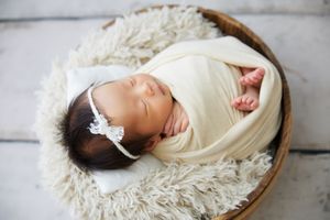 Newborn photography series showing baby wrapped in cream blanket on rustic wooden surface.