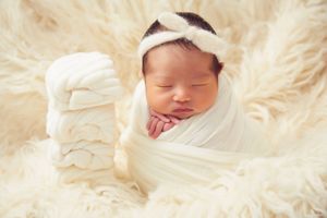 Newborn photography on cream colored fluffy textured backdrop.
