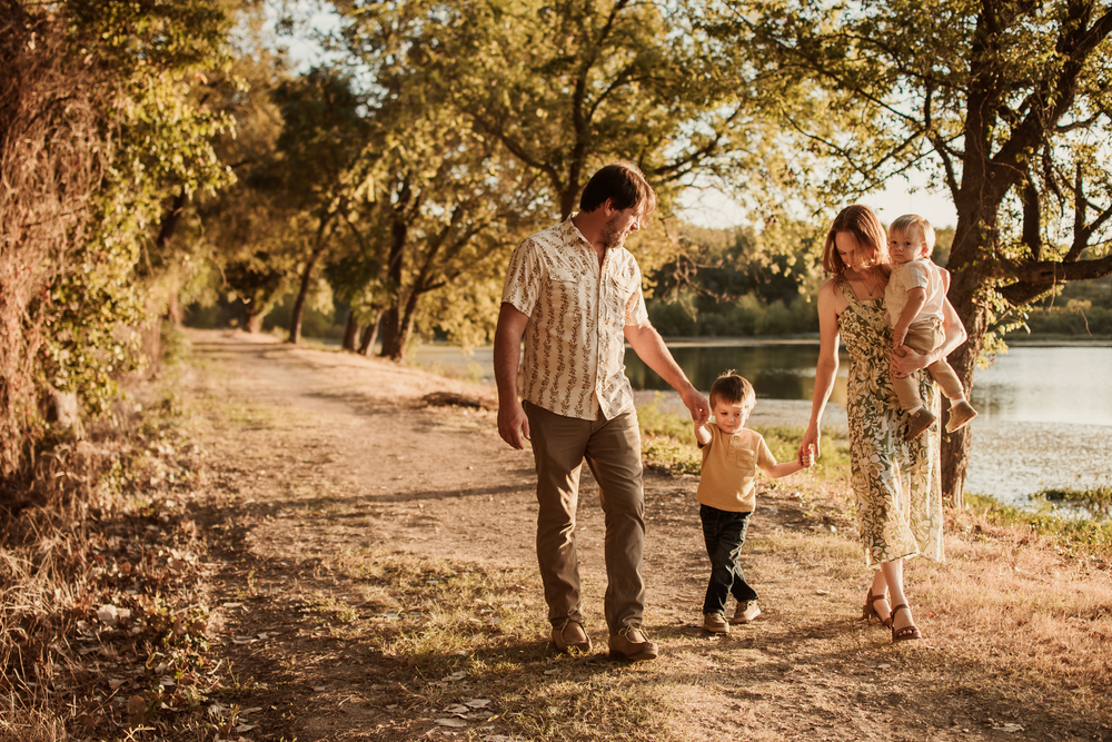 Family walks together along a sunlit autumn path during golden hour photography session.