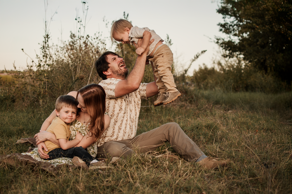 A series of romantic outdoor portraits show a couple embracing on grassy terrain at sunset.