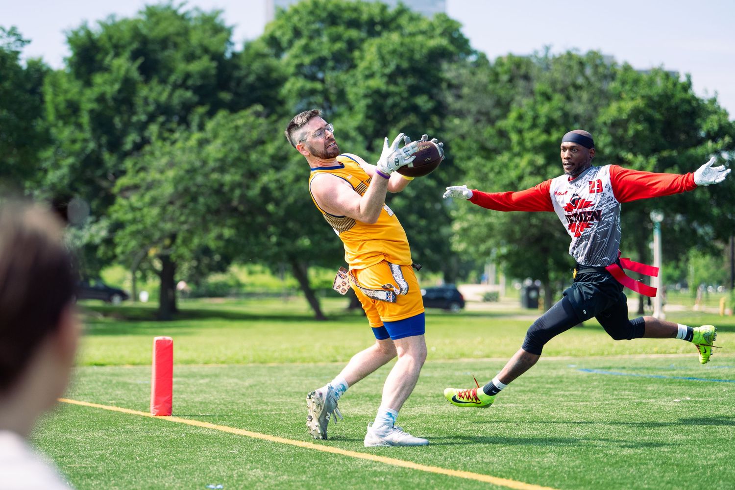 An athlete reaches for the football falling into his arms, trailed by an opponent at Pride Bowl in Chicago hosted by the NGFFL