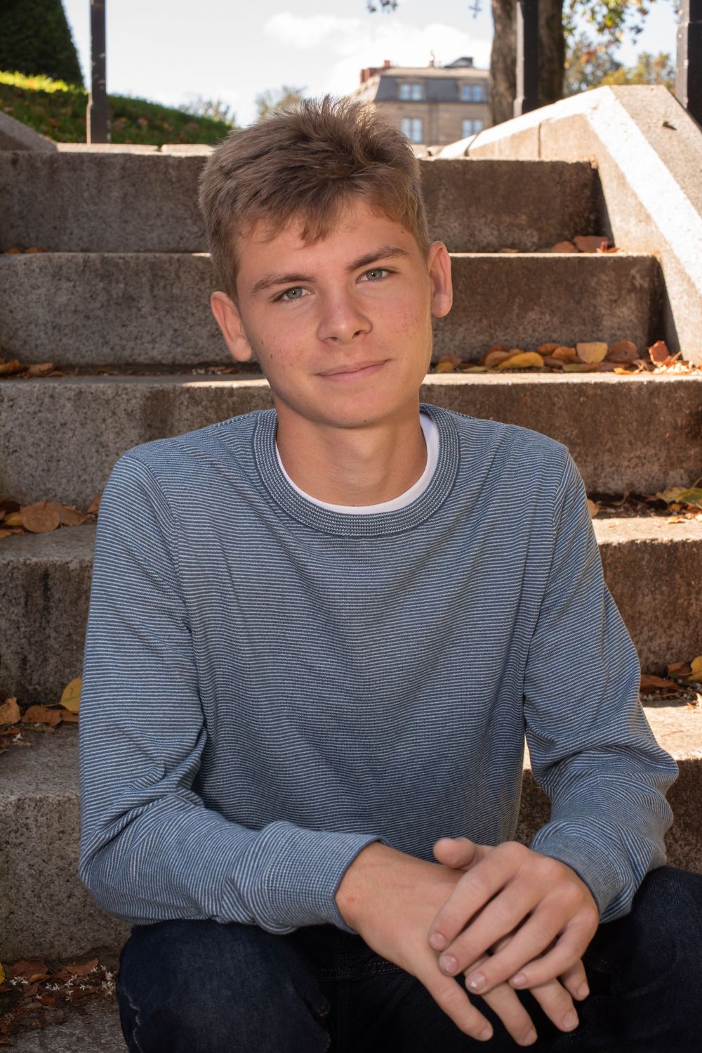 A series of four connected photos showing someone in a blue-gray sweater sitting against a concrete wall in sunlight.