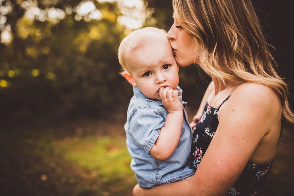 A tender moment captured between parent and child in golden sunlight during an outdoor photo session.