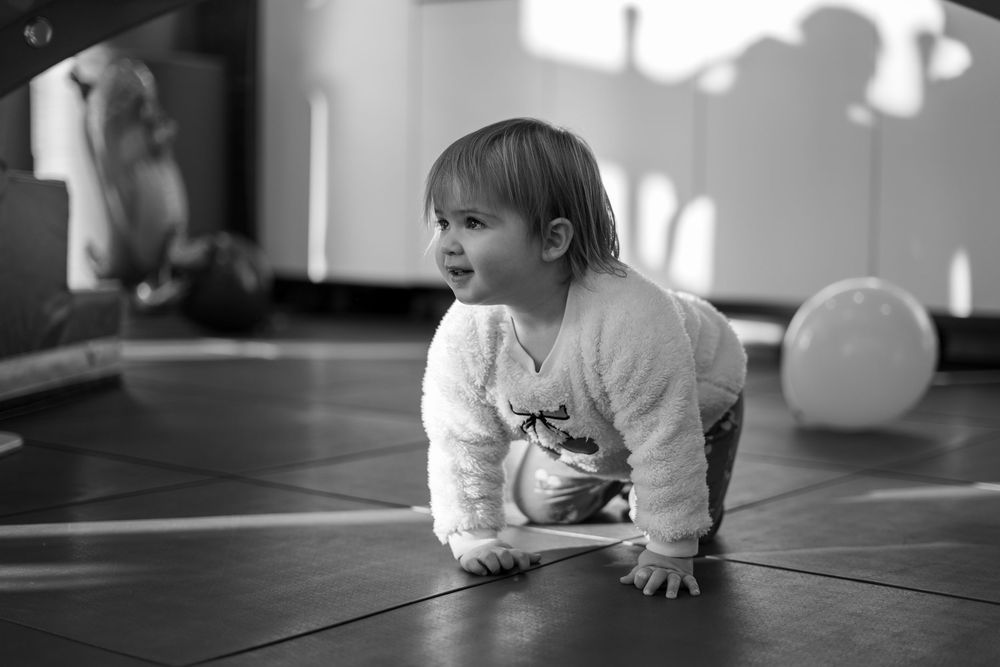 A sequence of black and white photos shows a baby learning to crawl and move across a hardwood floor.