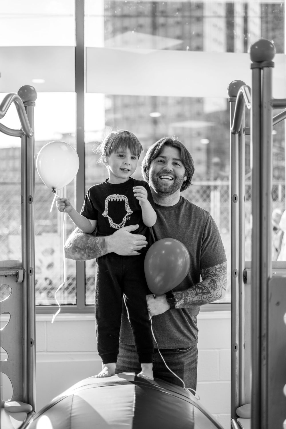 People playing with balloons in a modern building interior, shown in black and white.