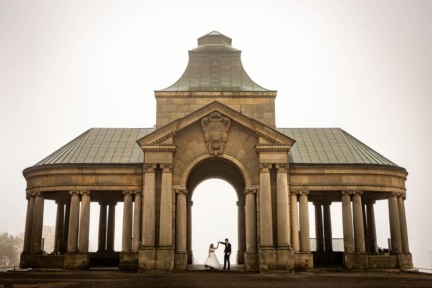 Classical stone pavilion with columns photographed in atmospheric misty conditions.