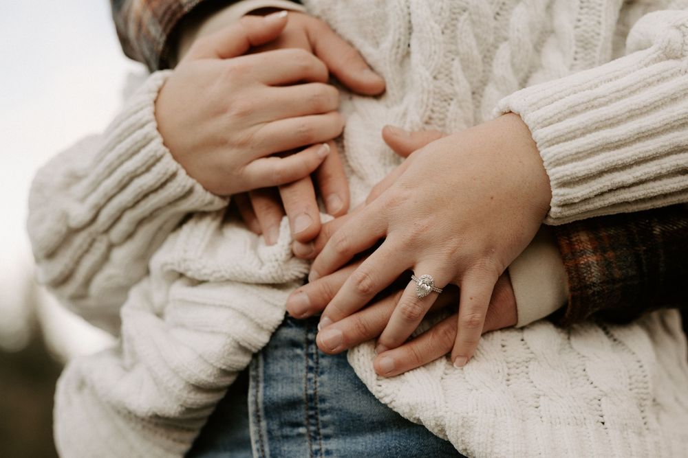Close up of hands gently embracing over a soft cream knit sweater background.