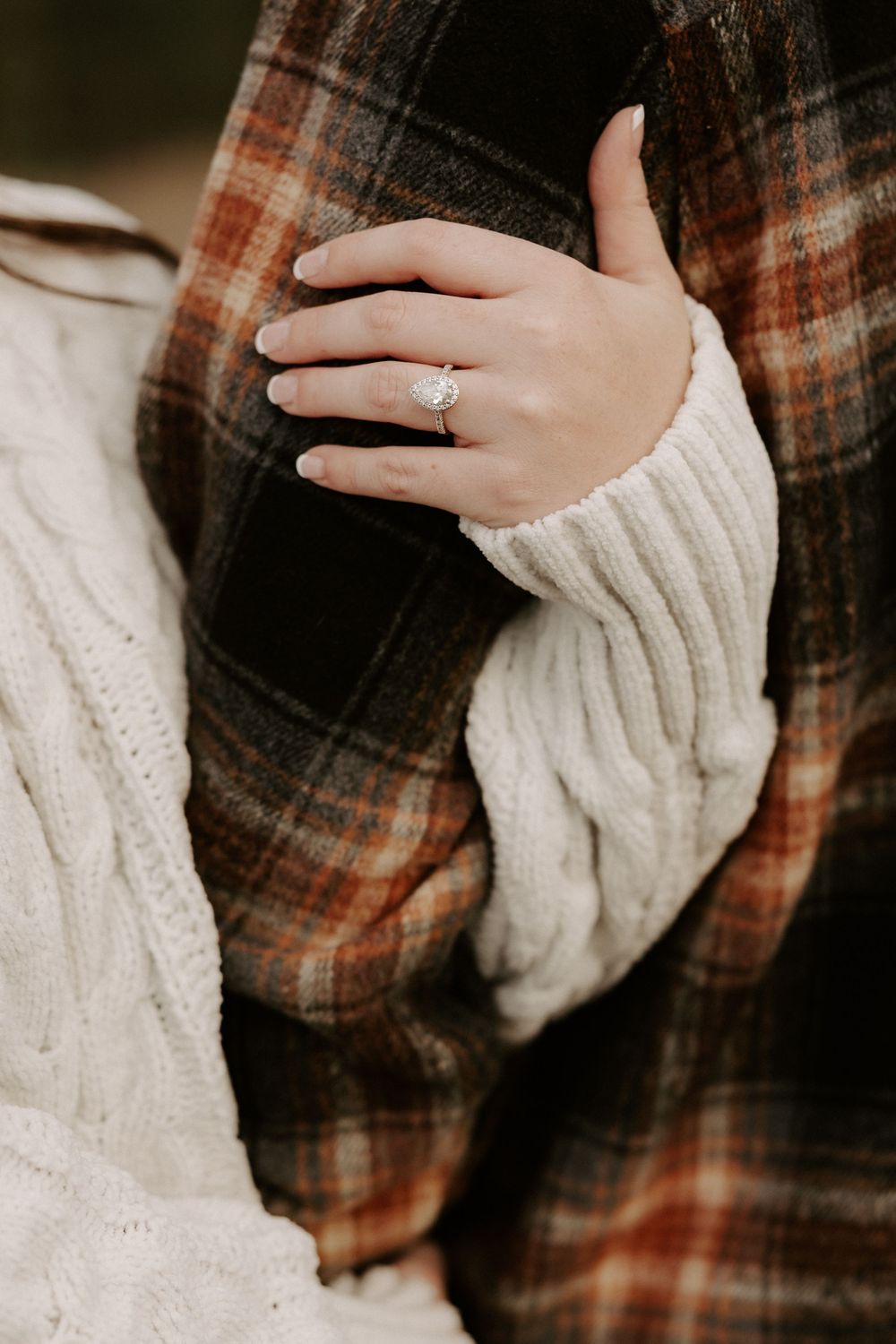 Close-up shots of hands in a white knit sweater against a plaid flannel shirt showing an engagement ring.