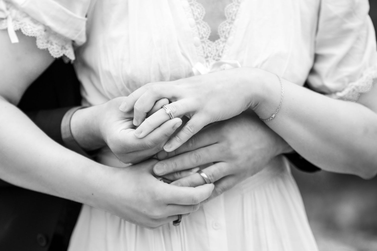 Black and white photo of a couple exchanging rings during an elopement wedding ceremony, close-up of their hands.