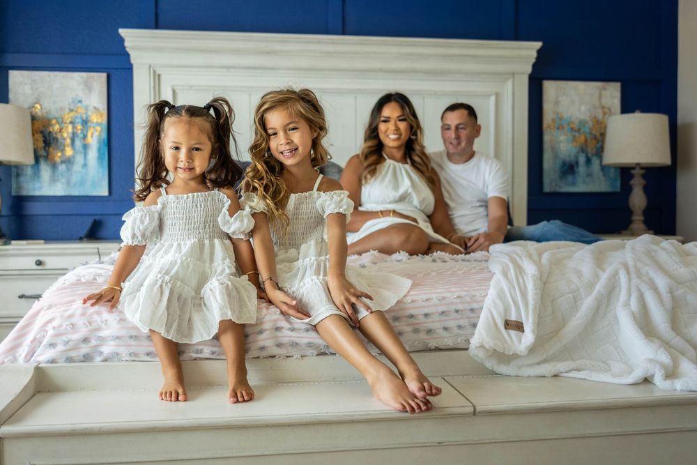 A family posing in their blue and white bedroom for a photo.