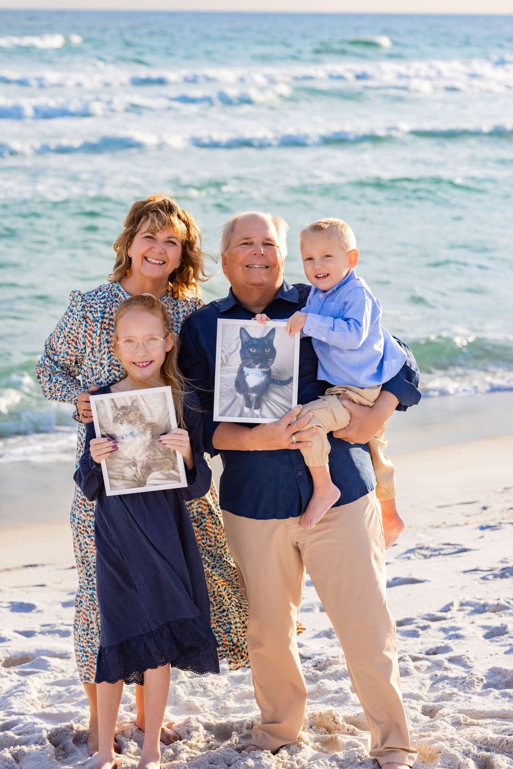 Family enjoying a playful moment together on a sunny beach with waves in the background.