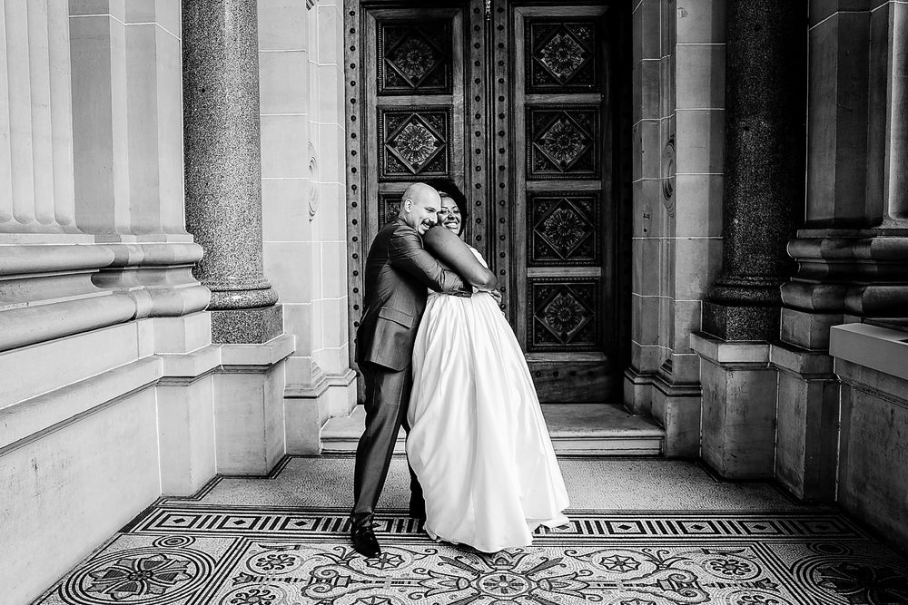 A black and white wedding photo series showing a couple posing on an ornate tiled entrance of a historic building.