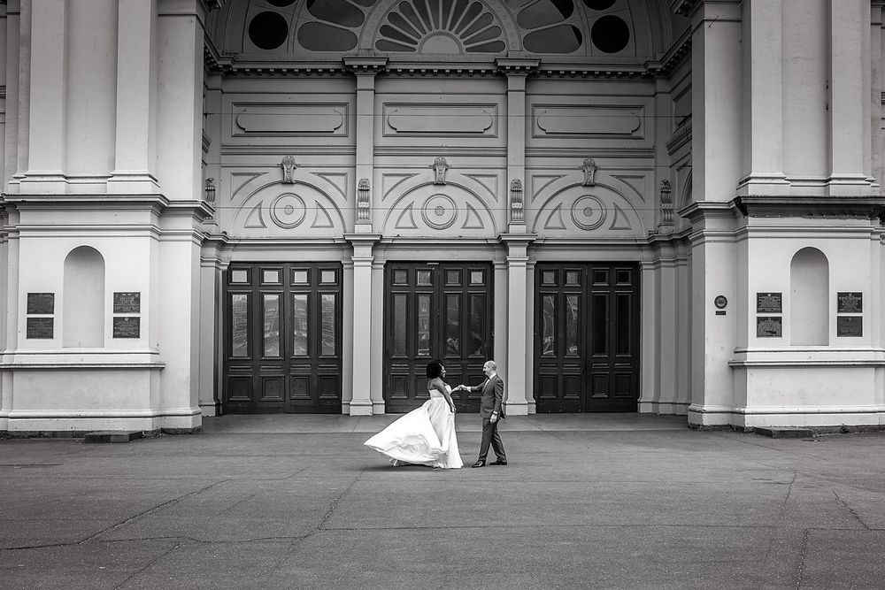 An elegant building entrance with ornate architectural details and symmetrical doors creates a grand wedding backdrop.