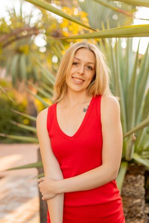 Red sleeveless dress photographed in front of tropical palm plants at golden hour.