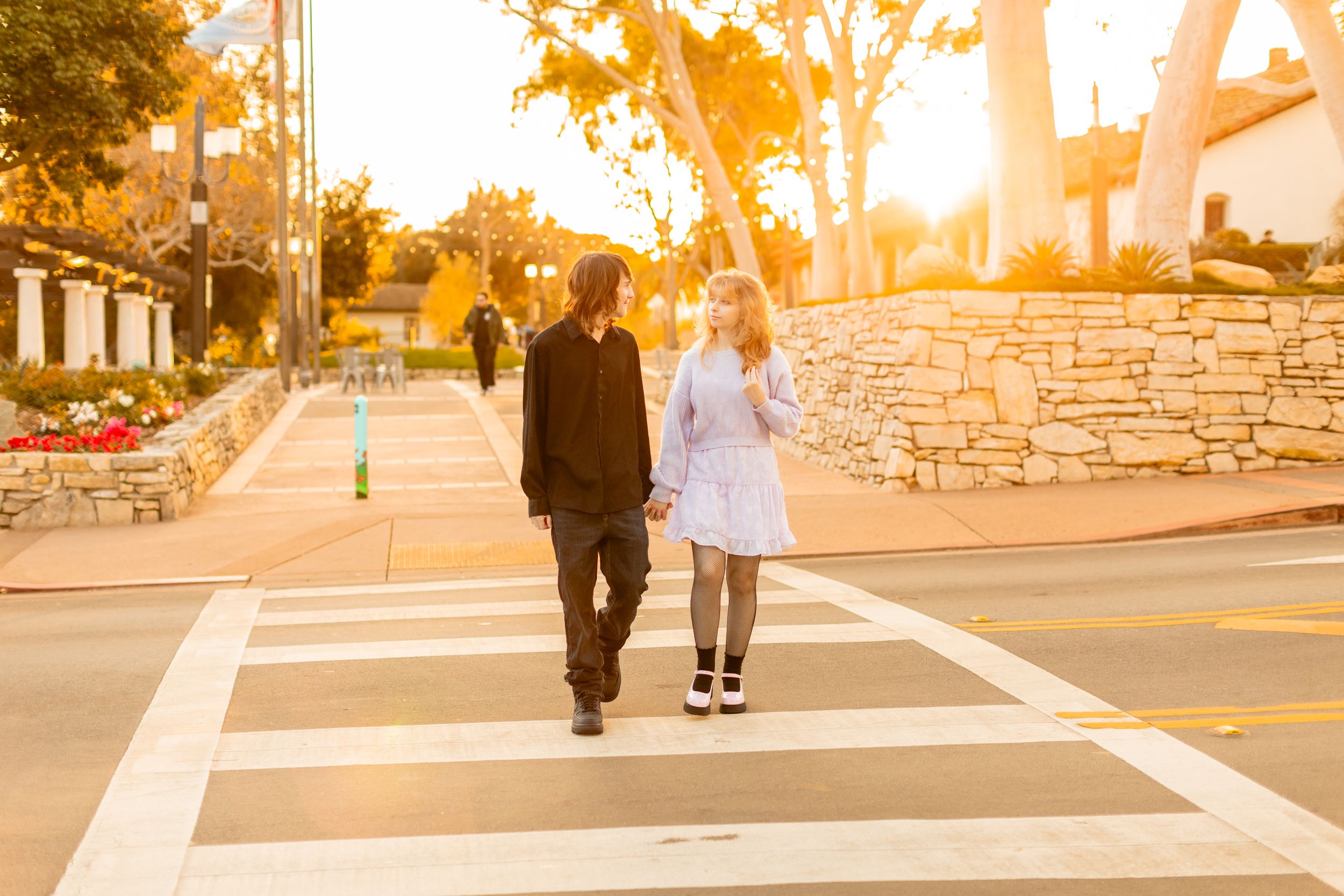 Two people walking together at sunset near Spanish colonial architecture.