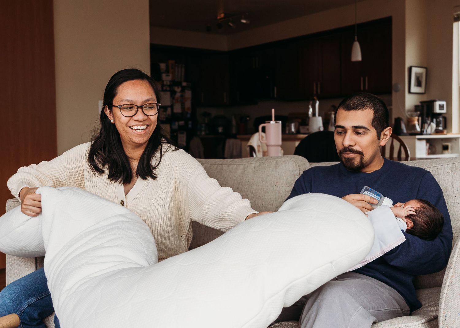 Bride in white dress gets ready for her wedding day with help from bridesmaids in a bright hotel room.