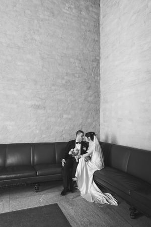 A series of four black and white photos showing two figures in white sitting on a dark couch against a bare wall.