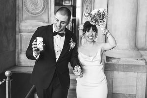 A couple shares a joyful moment during their wedding celebration in an elegant black and white photograph.