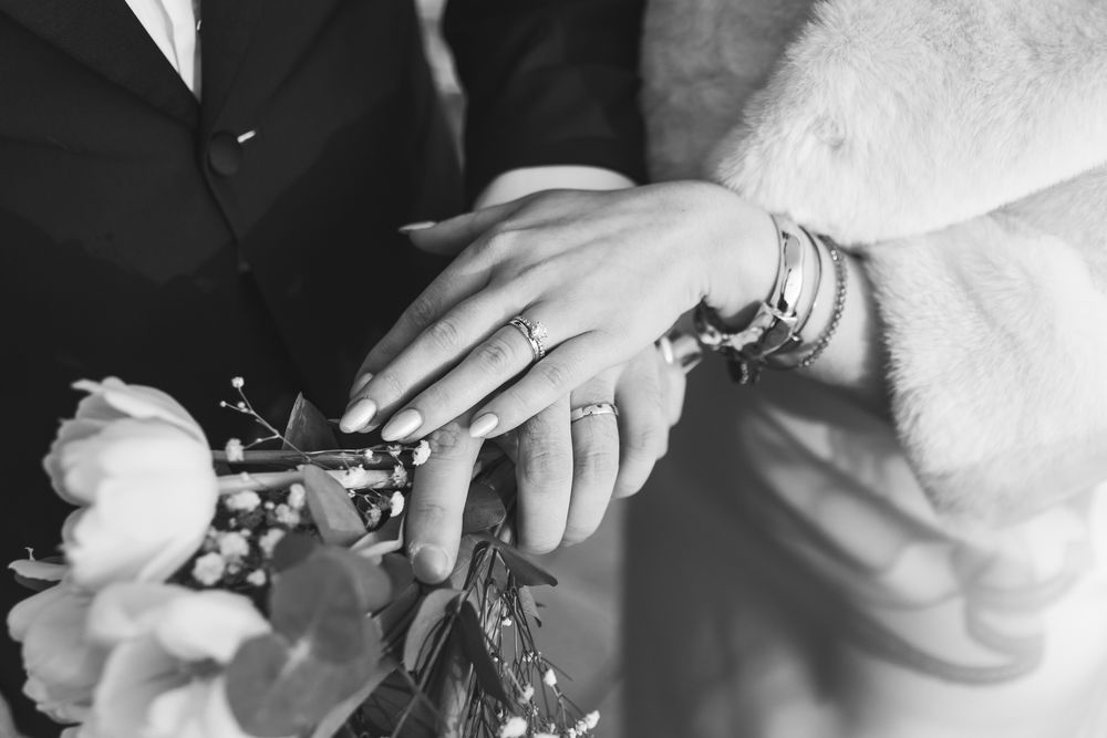 Close-up sequence showing hands putting on a diamond engagement ring in black and white photography.
