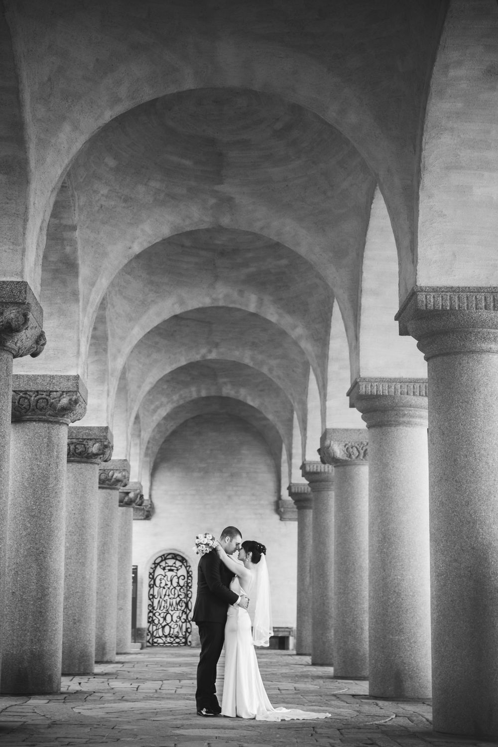 A series of black and white photographs showing a couple in formal attire under grand stone archways.