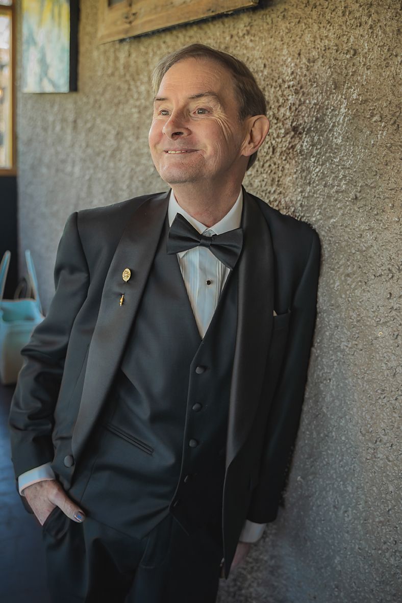 A sequence of four photos showing someone in a dark suit leaning against a textured wall.