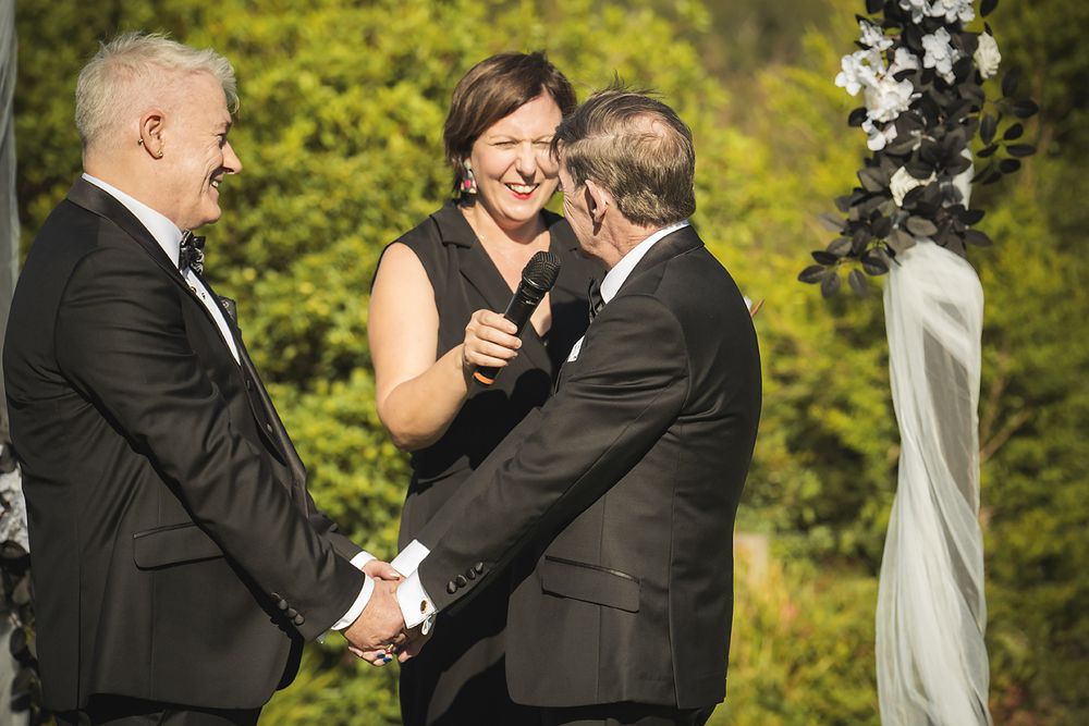 A couple shares an intimate moment during their wedding ceremony in a lush outdoor garden setting.