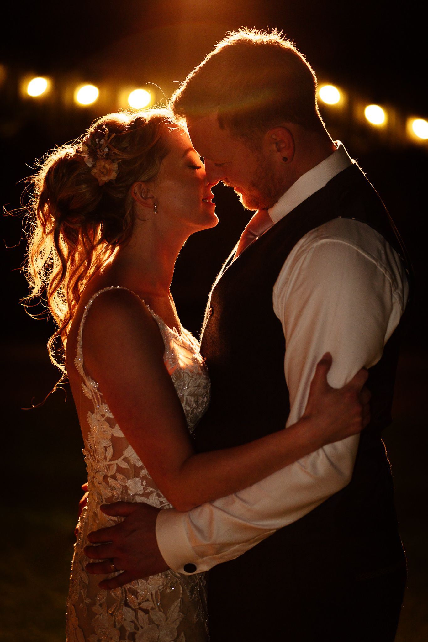 Silhouetted wedding couple shares tender moment under dramatic backlighting. Doxford Barns