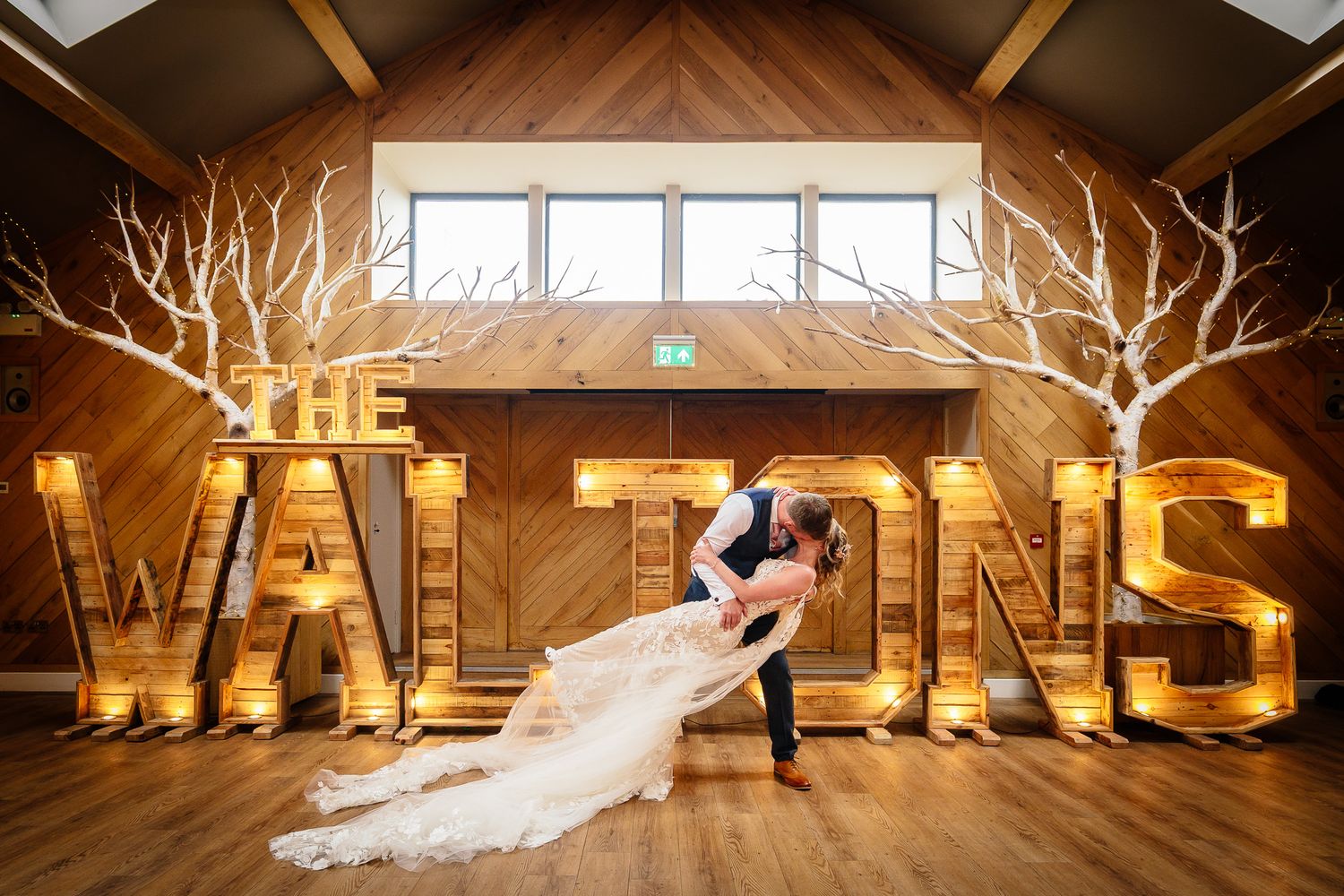 Artistic wedding venue shot with illuminated letters and rustic wooden beams.