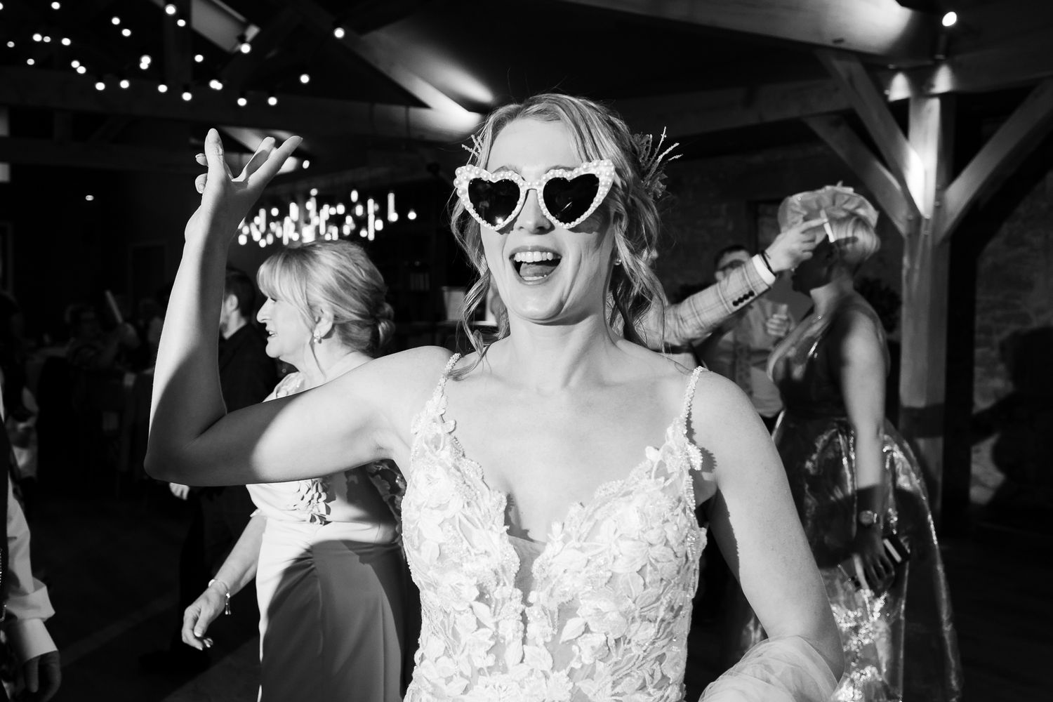 Wedding party dancing and celebrating at night with festive lighting.