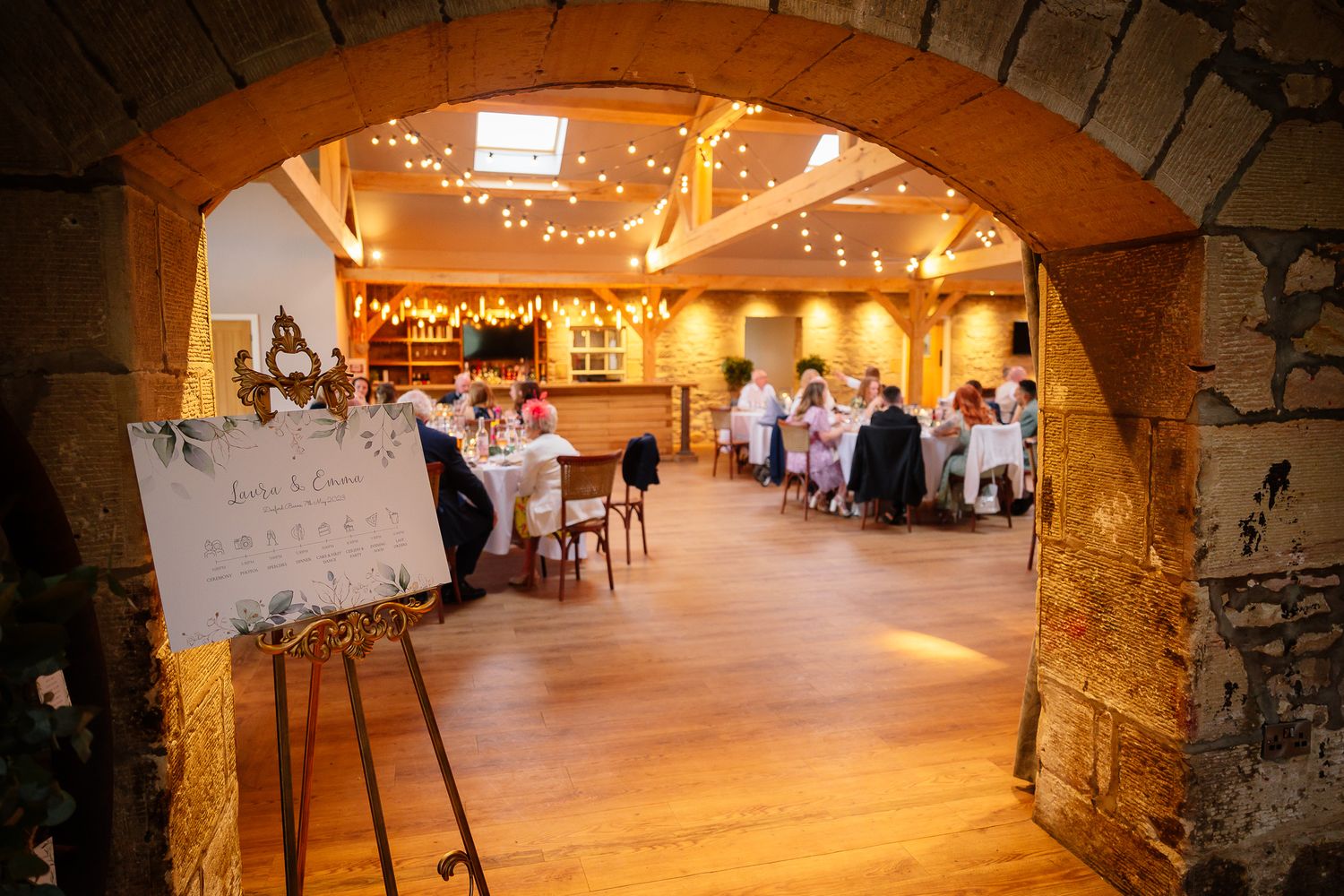 Stone archways frame an elegant rustic wedding reception space with warm lighting.