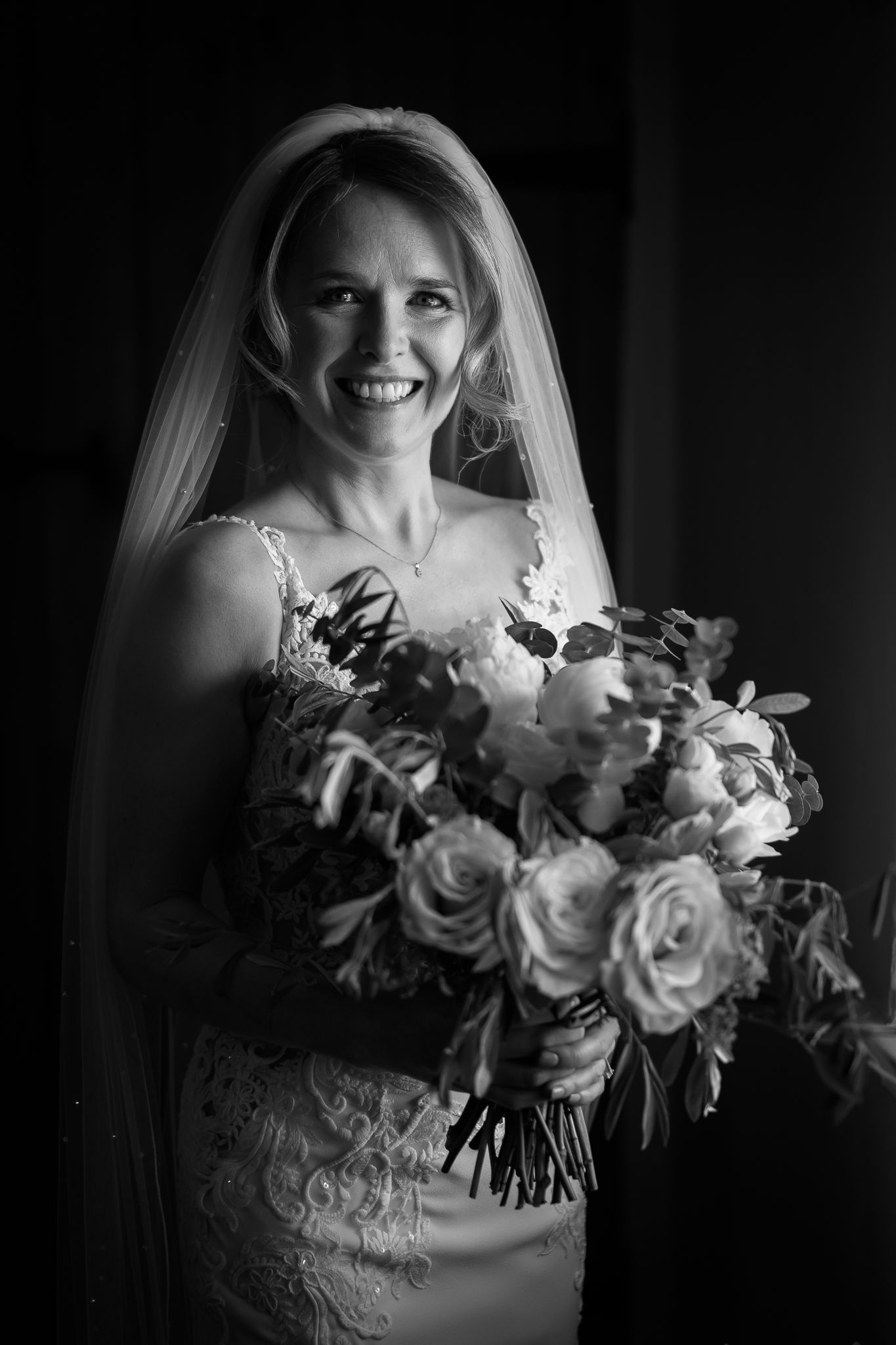 Elegant bridal bouquet of white roses and greenery captured in dramatic black and white.