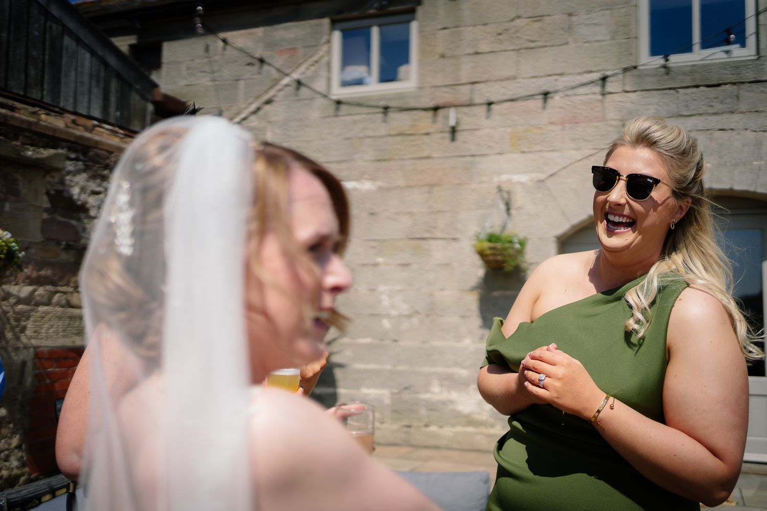 Outdoor wedding celebration with guests mingling in sunny courtyard.