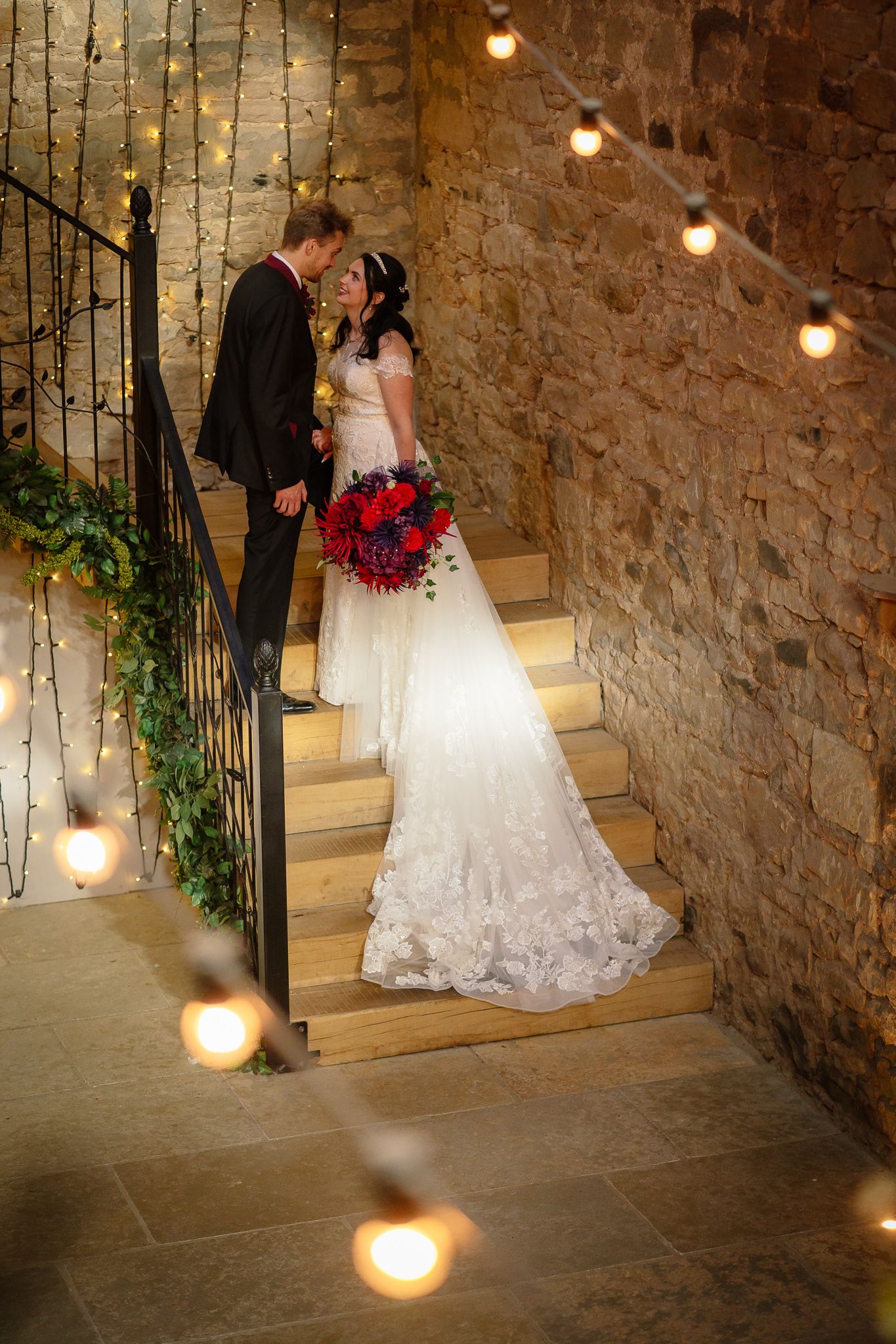 Stone-walled interior venue with string lights and elegant staircase creating a romantic atmosphere. Doxford Barns