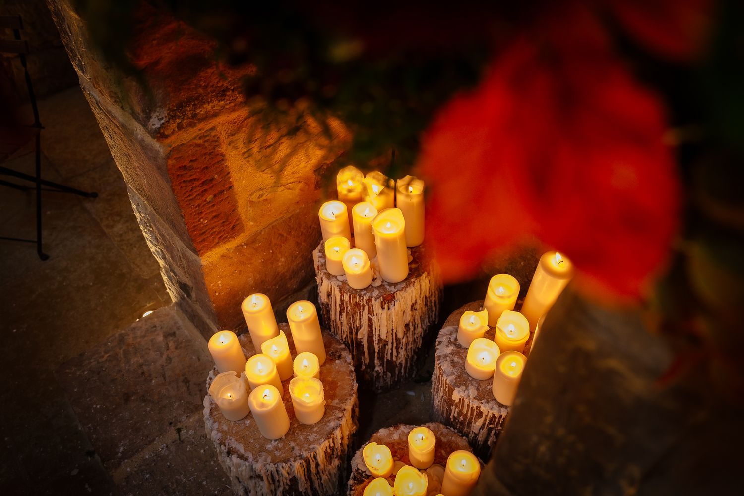 Glowing candles arranged on rustic wooden logs creating warm ambient lighting. Doxford Barns