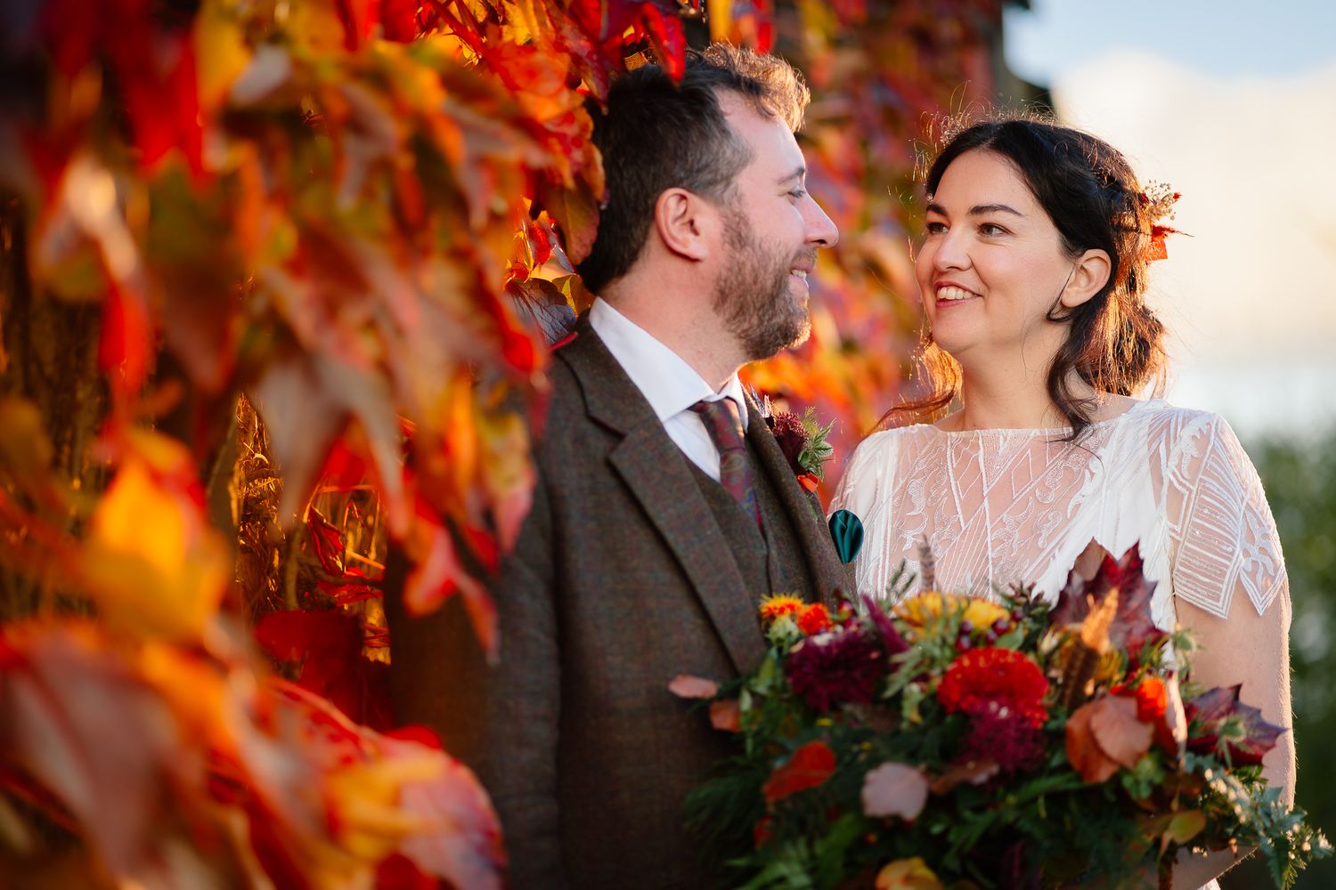 Autumn wedding portrait with vibrant red foliage in the background. Doxford Barns
