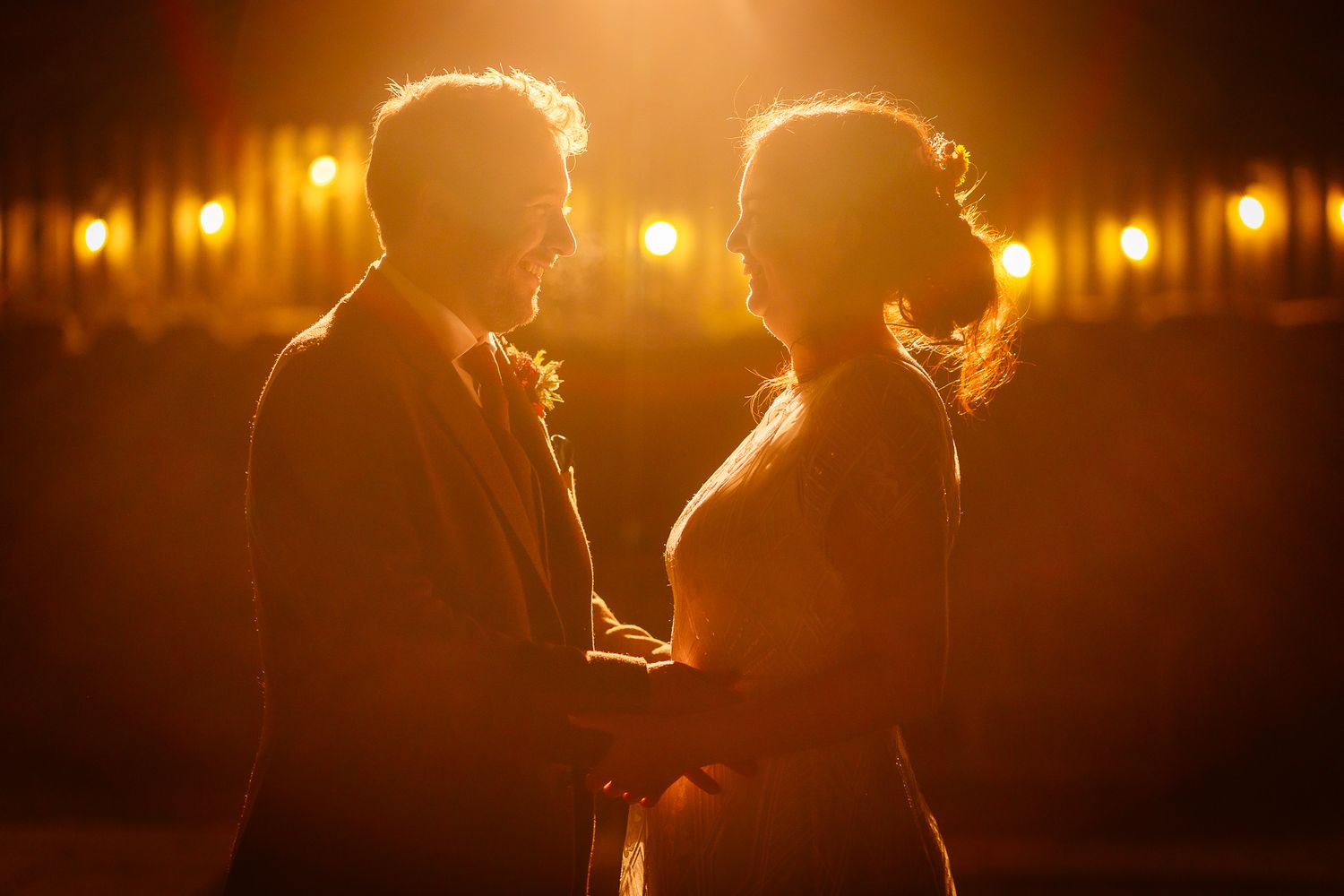 Wedding couple dancing in warm golden lighting at an evening reception. Doxford Barns