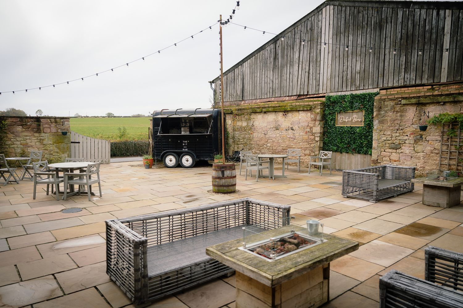 Outdoor stone patio venue with string lights and rustic decor. Doxford Barns