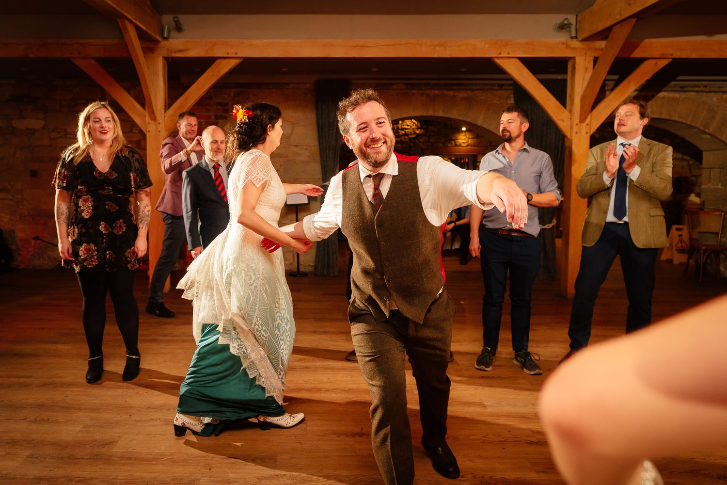 Wedding guests dancing energetically on wooden dance floor during reception. Doxford Barns
