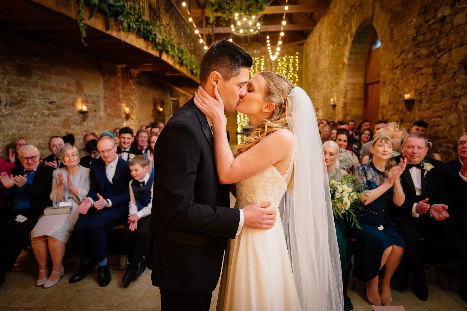 Wedding reception in rustic stone venue with guests celebrating. Doxford Barns