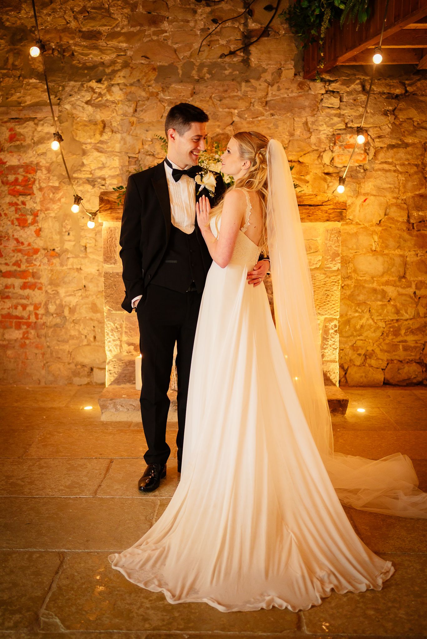 Couple sharing romantic moment in rustic brick venue with warm lighting. Doxford Barns